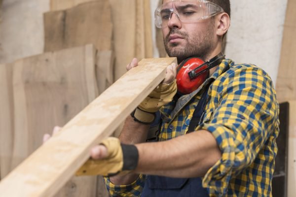 male-carpenter-seriously-looking-wooden-plank