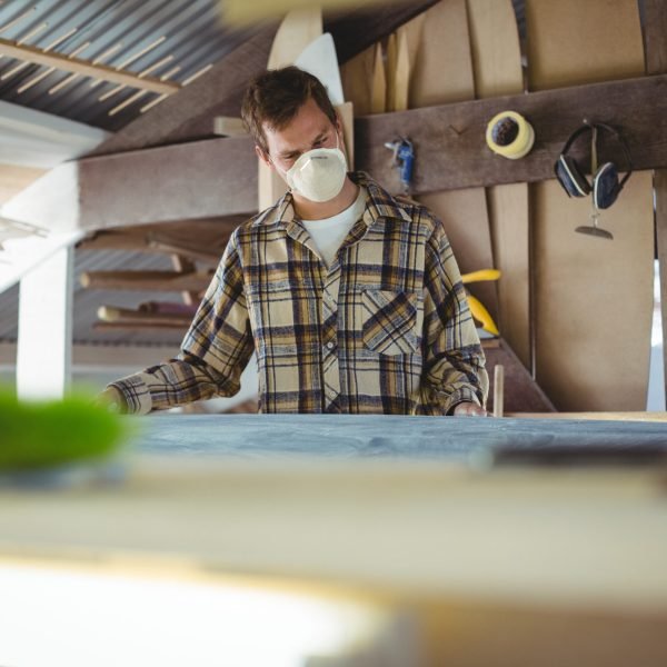Man making surfboard in workshop
